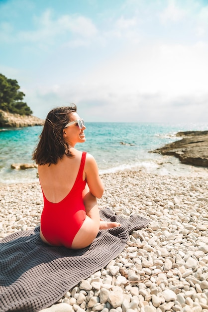 Woman sitting on blanket at sea beach