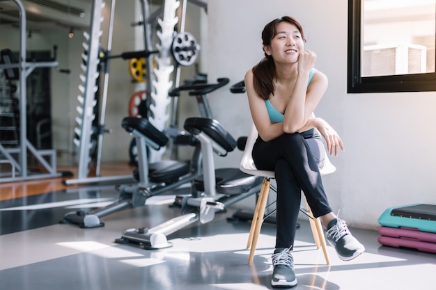 Woman sitting on a chair relaxing after workout in the gym.