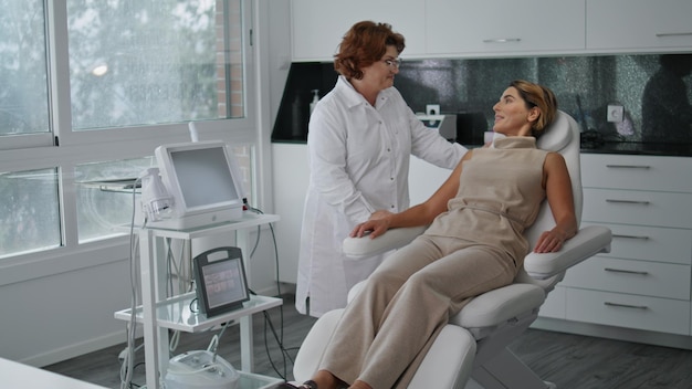 Woman sitting cosmetology appointment in clinic client talking dermatologist