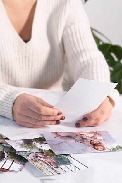 Woman sitting at desk and looking at printed photos remember nostalgia for a day of rest photography cards background Mock up