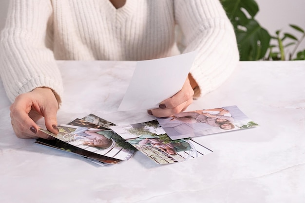 Woman sitting at desk and looking at printed photos remember nostalgia for a day of rest photography cards background Mock up