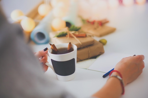 Woman sitting on the desk with christmas gift box Hands of woman