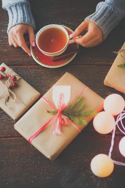 Woman sitting on the desk with christmas gift box Hands of woman