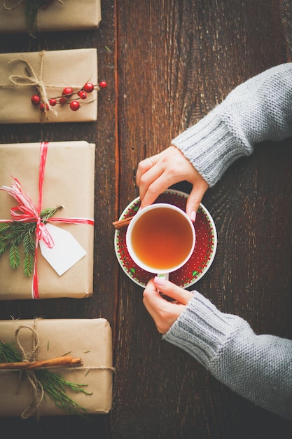 Woman sitting on the desk with christmas gift box Hands of woman