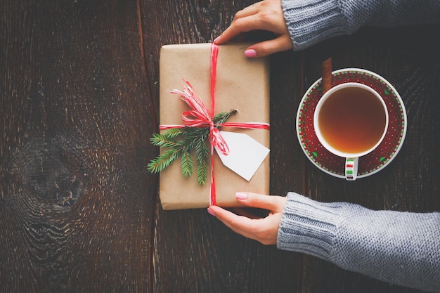 Woman sitting on the desk with christmas gift box Hands of woman