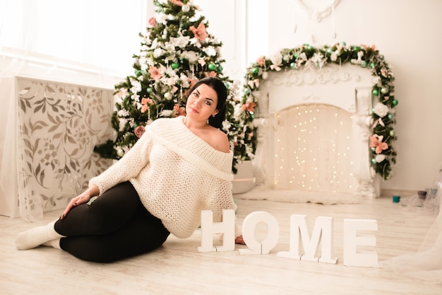 Woman sitting on the floor with a christmas tree