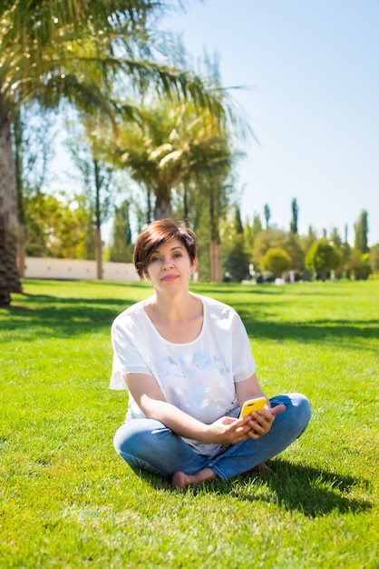 Woman sitting on the grass under palm trees with a laptop