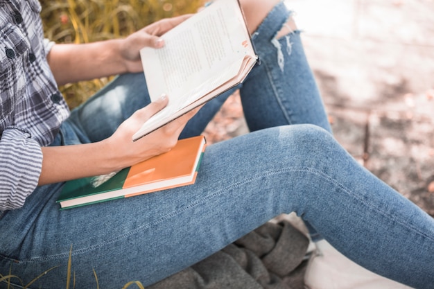 Photo woman sitting on grass with book in hands