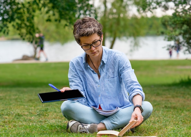 Woman sitting on green grass and studying