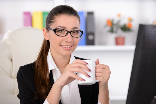 Woman sitting at her working place and drinking coffee.