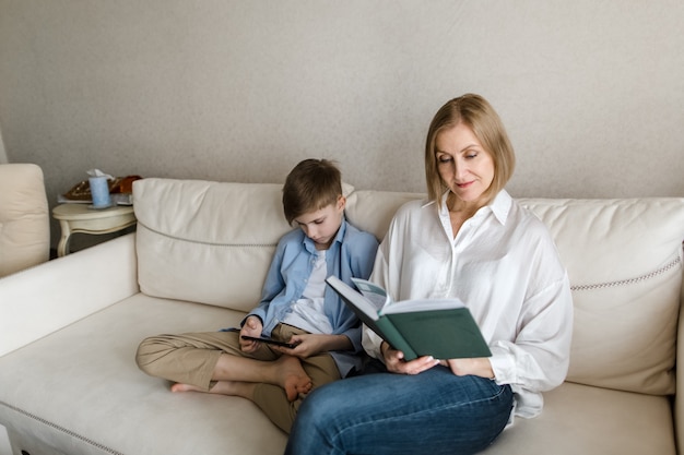 Woman sitting holding book in her hand and guy is holding phone