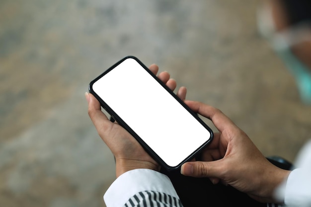 Woman sitting holding a smartphone blank white screen at the office Mock up for text message or information