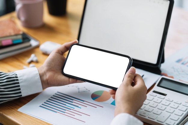 Woman sitting holding a smartphone blank white screen at the office. Mock up