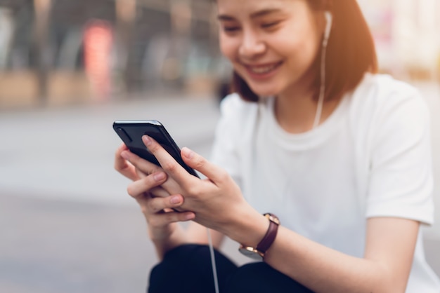 Woman sitting and holding a smartphone, using cell phone on lifestyle.