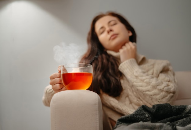 Woman sitting at home on the sofa unhealthy with a cup of hot tea