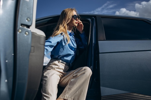 Woman sitting inside her electric car with open door