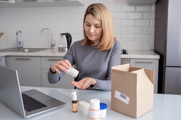 A woman sitting in the kitchen with food additives with a laptop