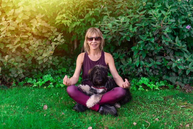 Woman sitting on the lawn with her Catalan shepherd dog performing meditation and yoga exercises