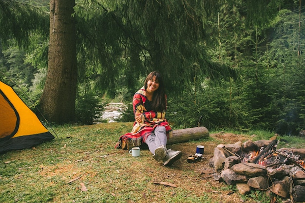 Woman sitting near fire with cup of tea