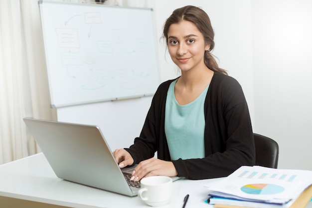 A woman sitting in an office works with financial reports and charts.