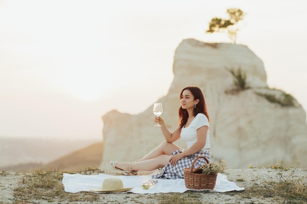 woman sitting outdoor in the mountain with wine glass in hand