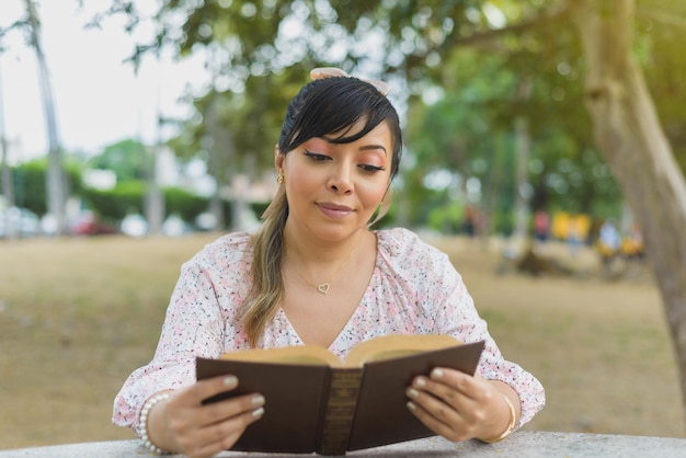 Woman sitting at a park table reading a book World book day Concept of reading