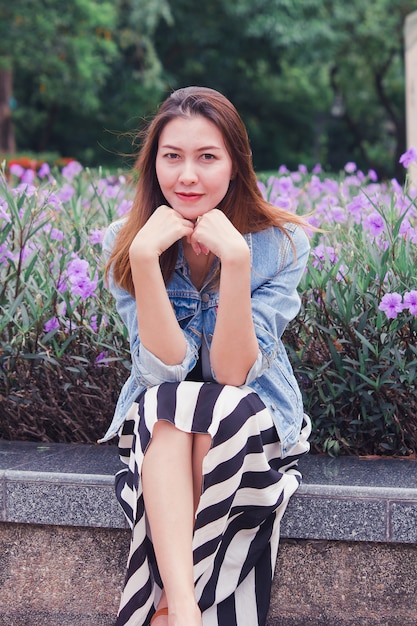 Woman sitting in a park where flowers are blooming beautifully.