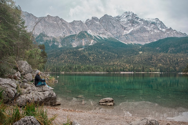 A woman sitting on the rocks near the lake. Alps Germany.