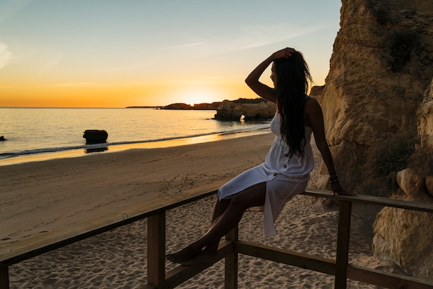 Woman sitting in a runway looking the sunset in the beach in Algarve, Portugal