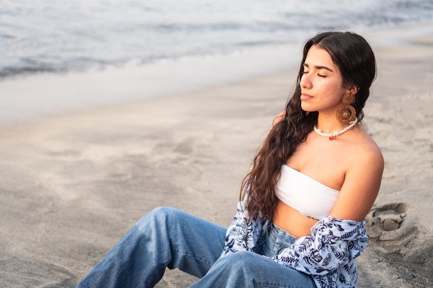 Woman sitting on the sand on the beach laughing