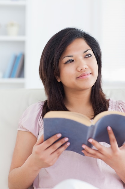 Woman sitting on a sofa while she holds a book