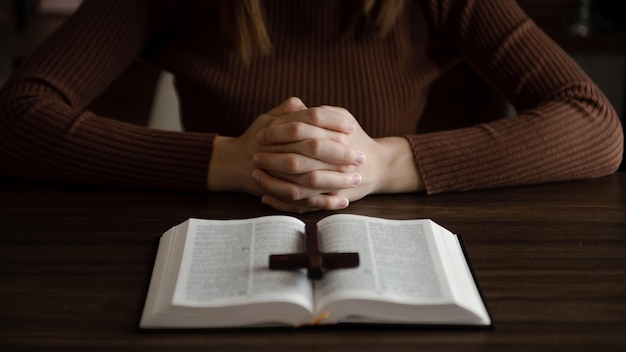 Woman sitting and studying the scripturesThe wooden cross in the hands Christian education concepts The Holy Scriptures open and pray to GodxA