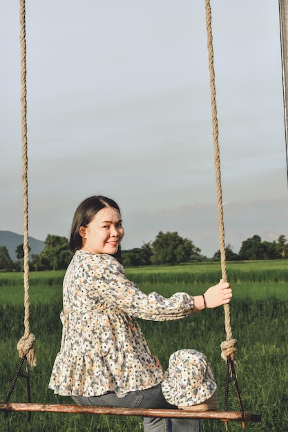 Photo woman sitting on swing at playground against sky