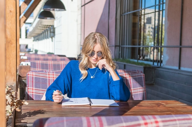 woman sitting at a table in a cafe with an open notebook on the table