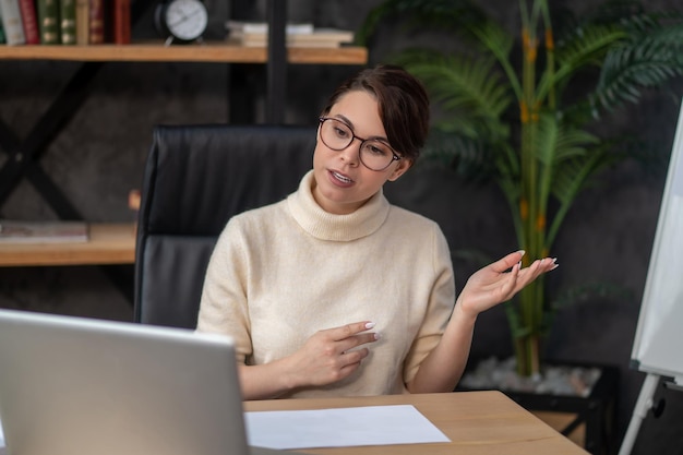 A woman sitting at the table and having a video call