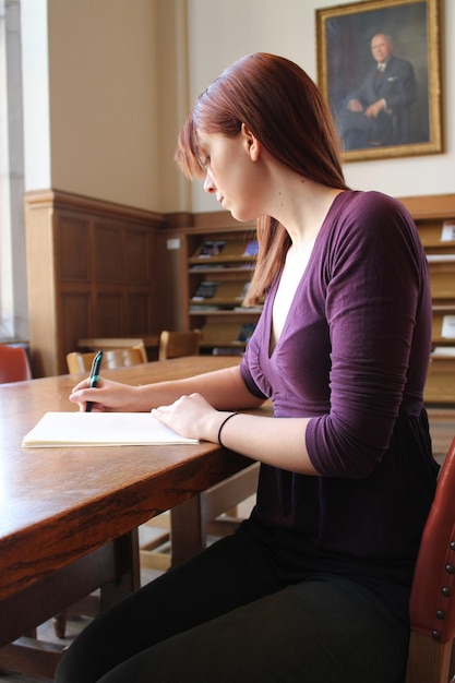 a woman sitting at a table writing in a book