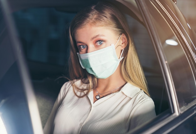 woman sitting in the taxi with a mask