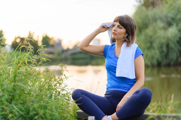 Woman sitting tired after fitness time in city park