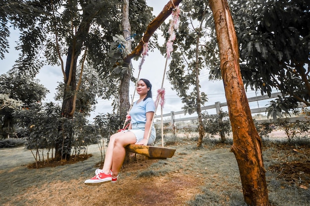 Photo woman sitting on tree trunk against trees