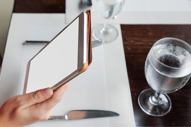 Photo woman sitting using a tablet on dining table in restaurant