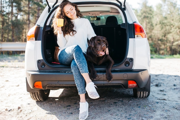 Woman sitting with her dog in open trunk