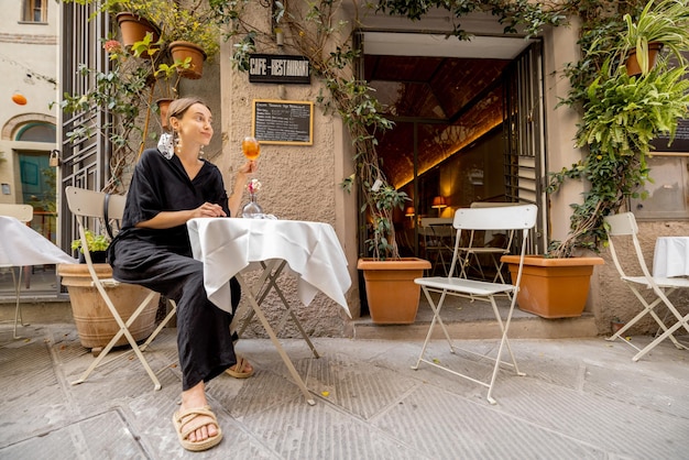 Woman sitting with wine at italian restaurant on cozy street