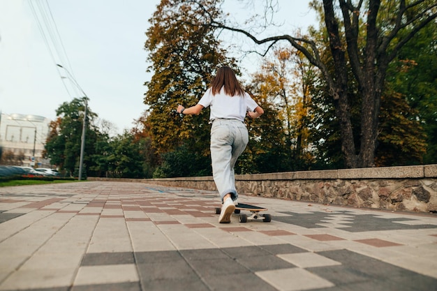 Woman skater walks on a longboard around the city