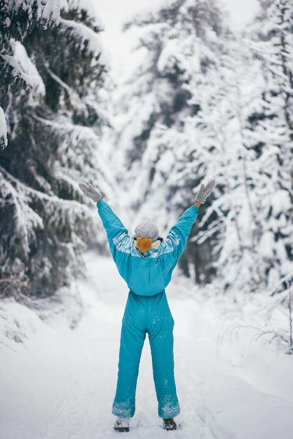 Woman in ski suit in snowy forest during winter vacations outdoors