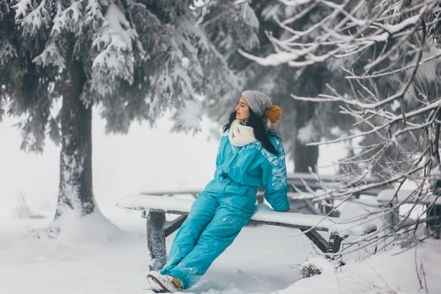 Woman in ski suit in snowy forest during winter vacations outdoors