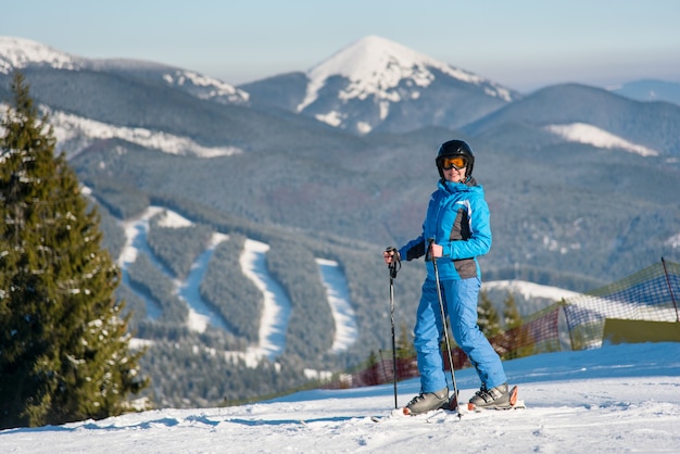 Woman skier smiling joyfully to the camera while skiing in the mountains at winter ski resort