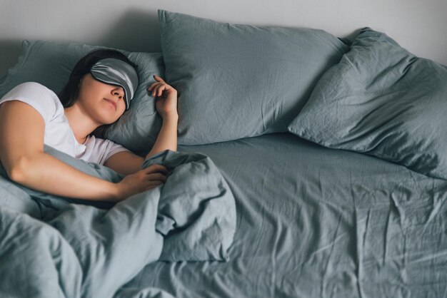 woman sleep in eye patch in grey bed copy space