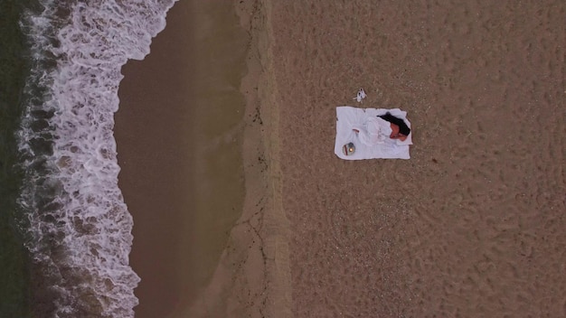 Woman sleeping on beach in bed in sunset