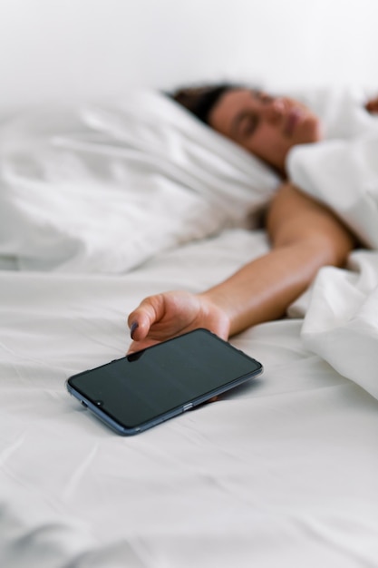 Woman sleeping in bed phone in her hand