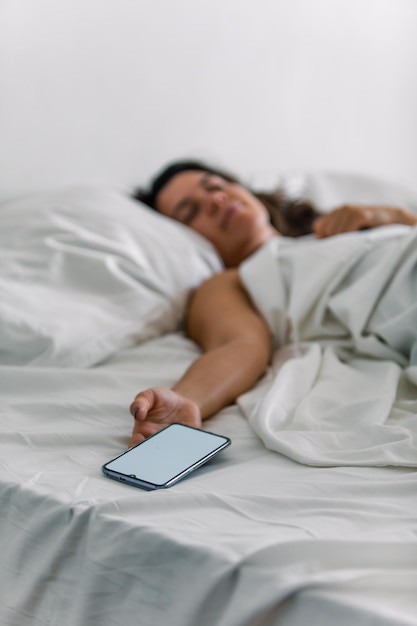 Woman sleeping in bed phone in her hand